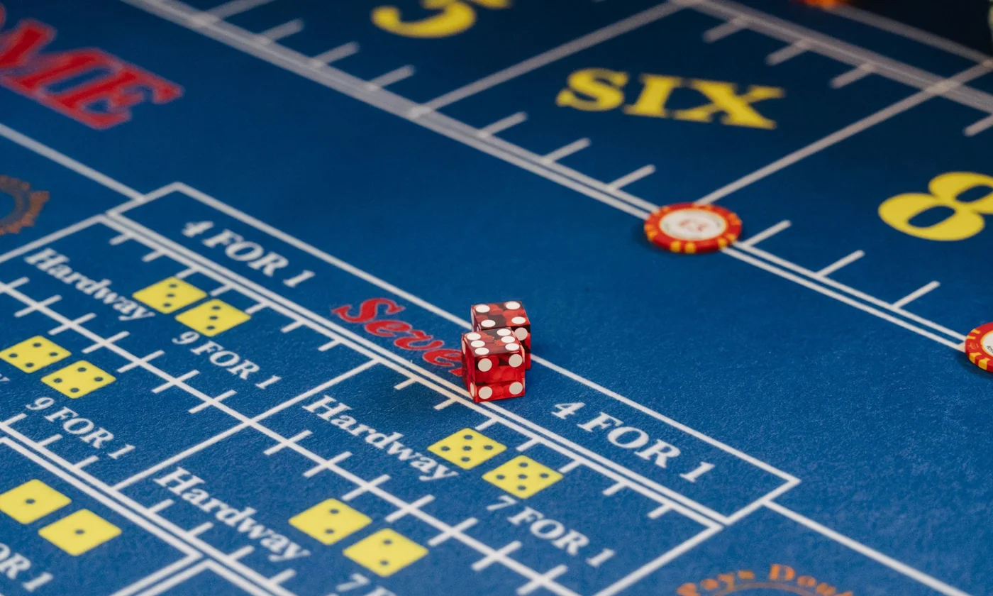 A blue Craps layout mid-shot, two red dice on the Seven line with SIX and 8 place bets in yellow