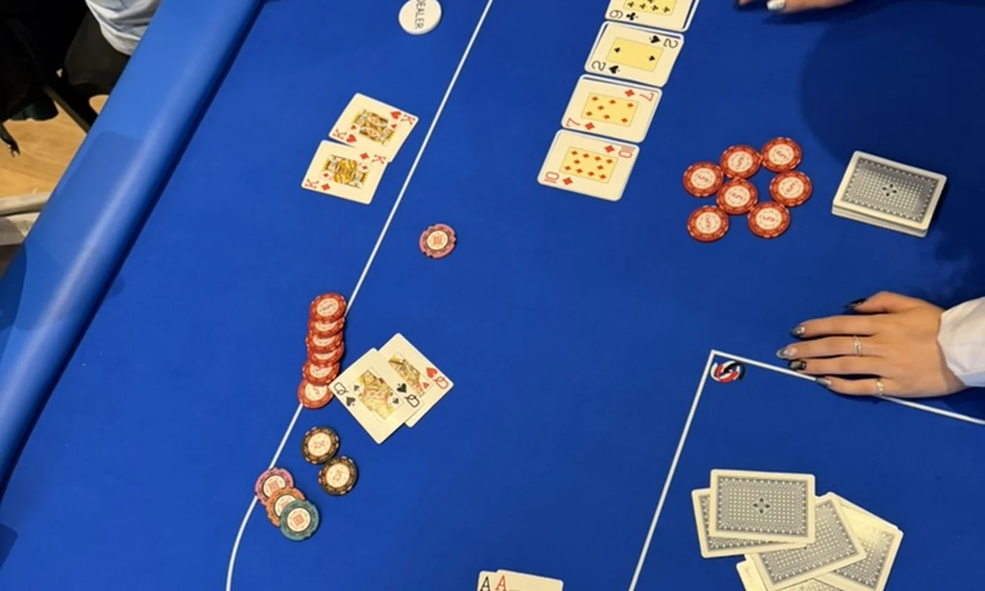 A blue Texas Hold'em layout mid-hand, community cards laid out with player pockets, chip stacks and the dealer button